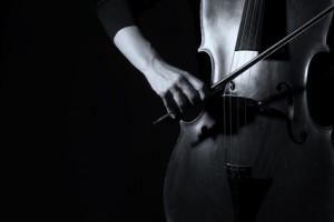 Beautiful woman holding a cello with selective light in black dress artistic conversion